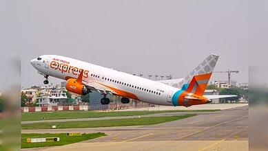 Air India Express aircraft lifting off from runway with cityscape in background.