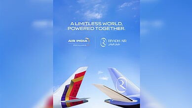 Air India and Riyadh Air aircraft tails flying in a clear blue sky with clouds.