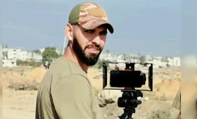 Al Jazeera cameraman Ahmed Washah stands outdoors beside filming equipment in the Gaza Strip.