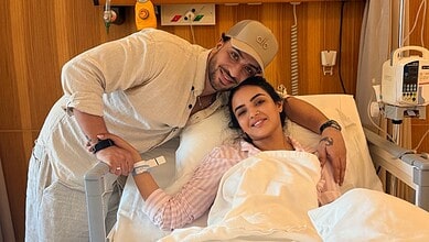 Jasmin Bhasin in hospital bed with a visitor, smiling and resting after treatment.