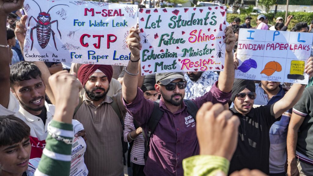 Protesters holding signs advocating for water leak solutions, student future, and government resignation.