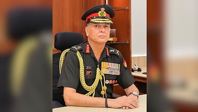 Senior military officer in formal uniform with medals and decorations, seated at a desk in an office sett.