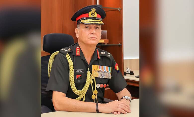 Senior military officer in formal uniform with medals and decorations, seated at a desk in an office sett.