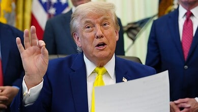 Donald Trump speaking and gesturing with his hand during a press event, surrounded by officials in the Wh.