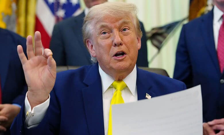 Donald Trump speaking and gesturing with his hand during a press event, surrounded by officials in the Wh.