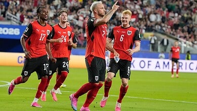 Austria football players celebrating during a match, wearing red and black kits.