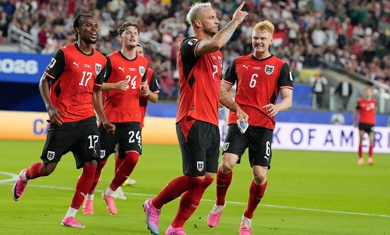 Austria football players celebrating during a match, wearing red and black kits.
