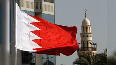 Bahrain national flag flying with a mosque in the background.