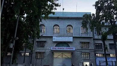 A woman walking past the historic Siasat Daily building in Hyderabad, showcasing its traditional architec.