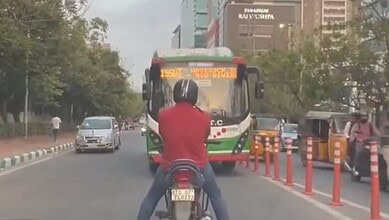 The image shows a bike rider refusing to allow a TGSRTC bus from moving from the wrong side of the road.