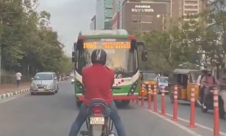 The image shows a bike rider refusing to allow a TGSRTC bus from moving from the wrong side of the road.