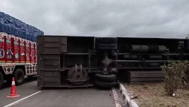 Overturned bus on Hyderabad-Kurnool highway with emergency cones and trucks nearby.