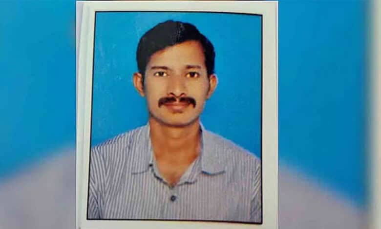 Portrait of a man with a mustache wearing a striped shirt, set against a blue background.