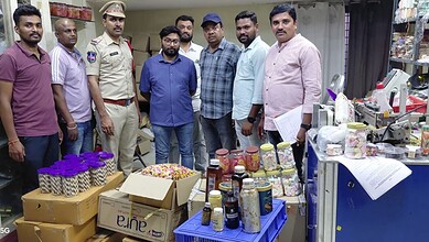 Group of men, including a police officer, standing behind a table with jars of food and drinks at a local.