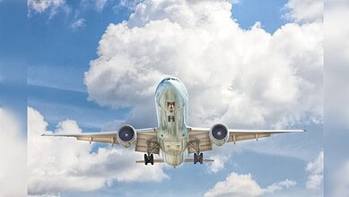 Passenger airplane flying high in the sky with clouds in the background.