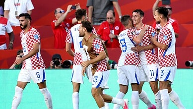 Croatian football players celebrating during a match, wearing checkered jerseys, in a stadium.