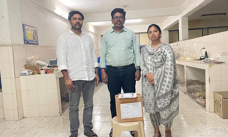 A woman and two men standing in a kitchen or food preparation area, with boxes and supplies around them.