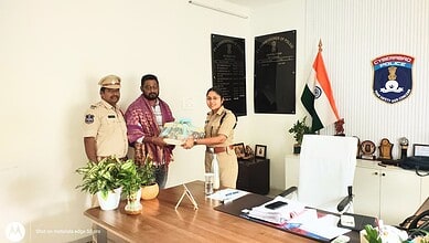 Police officer handing over documents to citizen in office, Siasat Daily news coverage.
