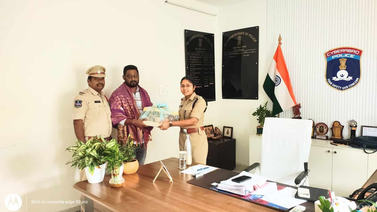 Police officer handing over documents to citizen in office, Siasat Daily news coverage.