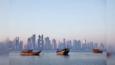 Qatar skyline with traditional wooden boats on the water, modern skyscrapers in the background.