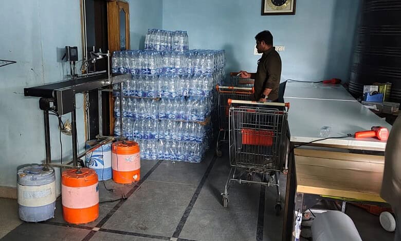 Worker checks bottled water stock at water unit in Hyderabad amid safety concerns.