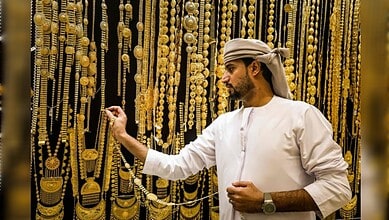 Man examining gold necklaces in a vibrant jewellery market.