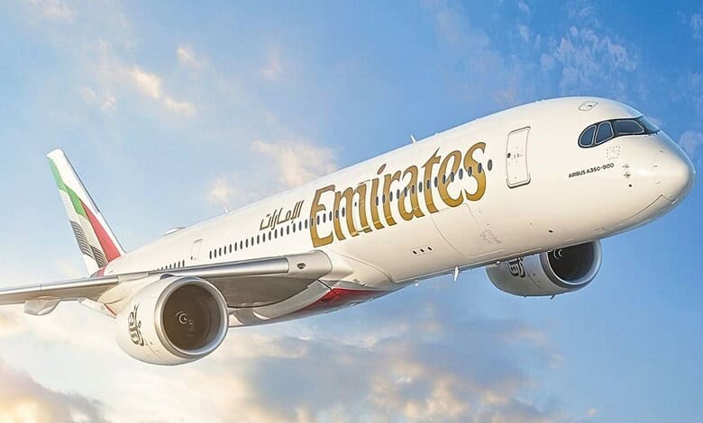Emirates Airbus A350-900 aircraft flying against a blue sky with clouds.