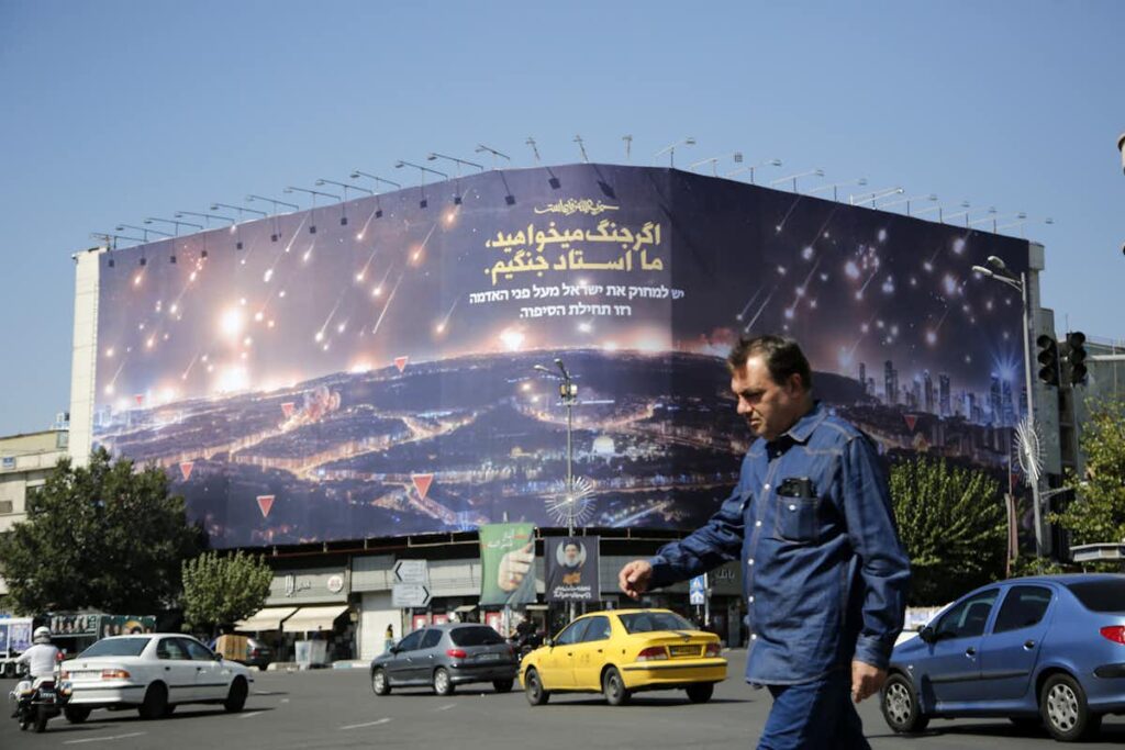 A large billboard in Enqelab Square, Tehran, depicts missiles streaking across the night sky over Israel as vehicles and pedestrians pass below, October 3, 2024.
