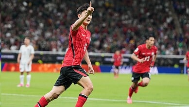 Football player in red jersey celebrating a goal on the field during a match.