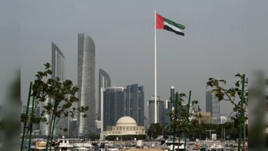 UAE flag flying over the Abu Dhabi skyline on a clear day.