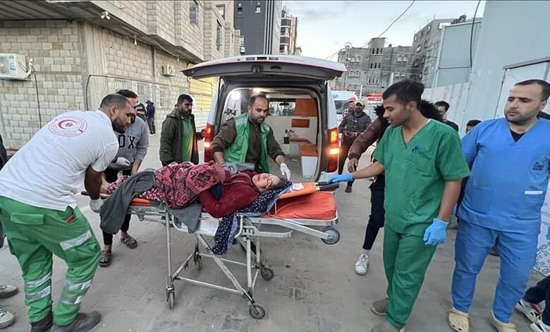 Medical workers transport a Gaza cancer patient on a stretcher outside a hospital beside an ambulance.