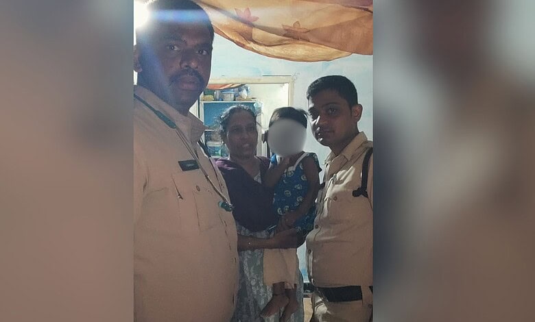 Police officers with a woman and child in a community setting.