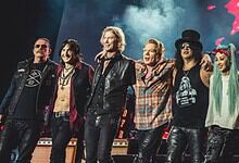 Vibrant rock band performing live on stage with energetic members and colourful lighting.