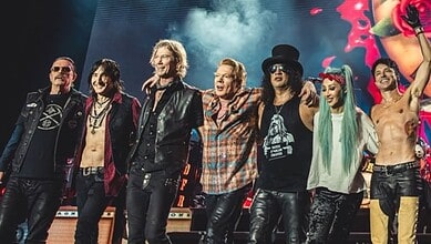 Vibrant rock band performing live on stage with energetic members and colourful lighting.