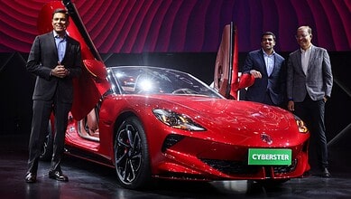 Elegant men showcasing a sleek red sports car on stage with a "Cyberster" sign, highlighting innovation a.