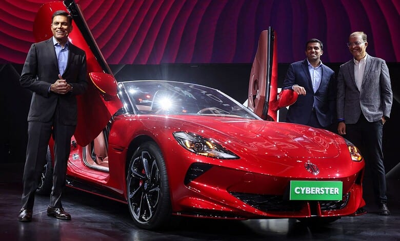 Elegant men showcasing a sleek red sports car on stage with a "Cyberster" sign, highlighting innovation a.