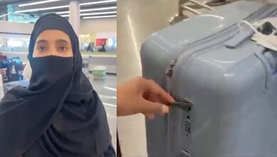 Woman in black hijab and face mask at airport terminal with luggage.