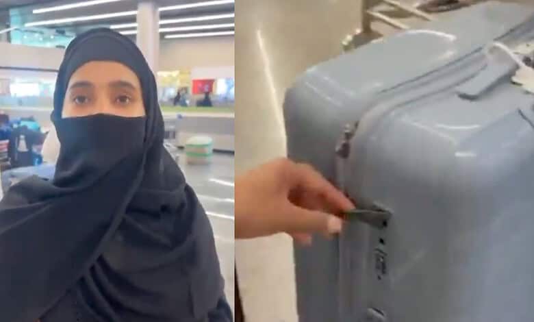Woman in black hijab and face mask at airport terminal with luggage.
