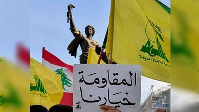 Hezbollah supporters hold the group's flags, the Lebanese flag and a placard reading "Resistance is our choice" during a protest in Beirut.
