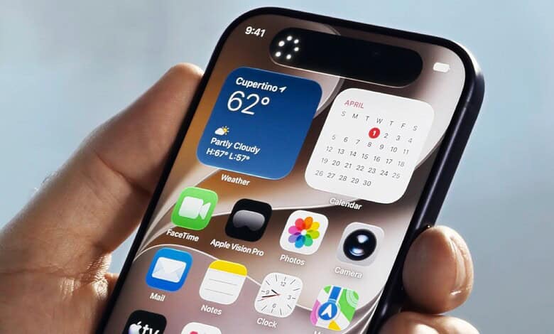 Smartphone displaying weather, calendar, and app icons, held in a person's hand against a blurred outdoor.