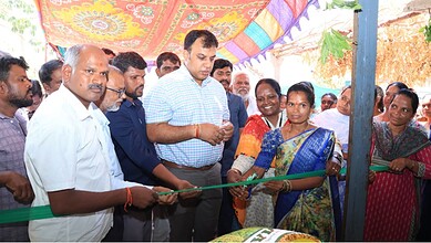 Group of people at the opening ceremony of the fertilizer retail outlet, with a woman cutting a ribbon.