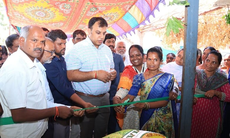 Group of people at the opening ceremony of the fertilizer retail outlet, with a woman cutting a ribbon.