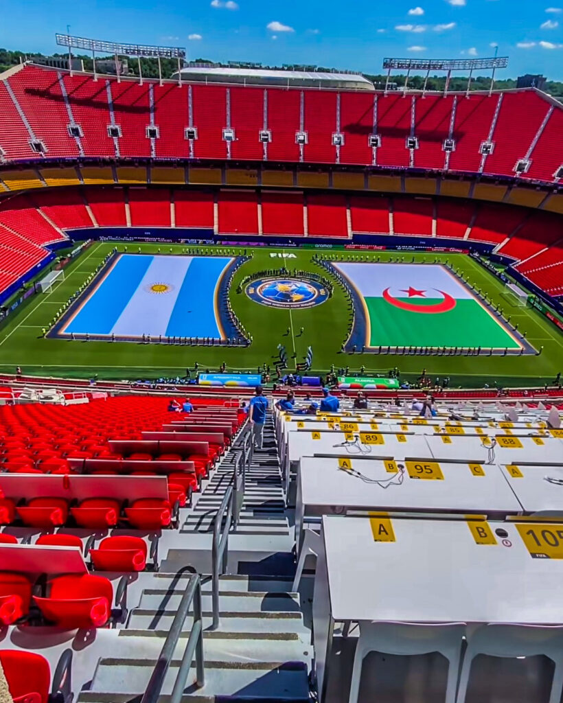 Empty football stadium with flags of Argentina and Algeria on the field.