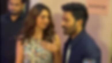 A celebrity couple engaged in conversation at a public event, with a blurred background.
