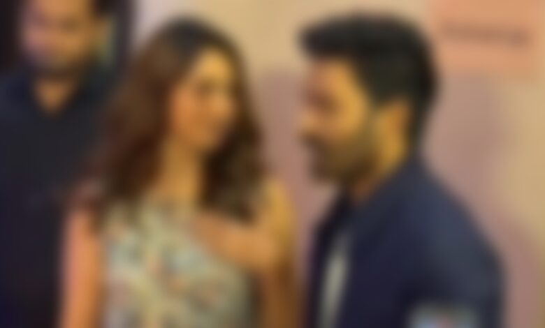 A celebrity couple engaged in conversation at a public event, with a blurred background.