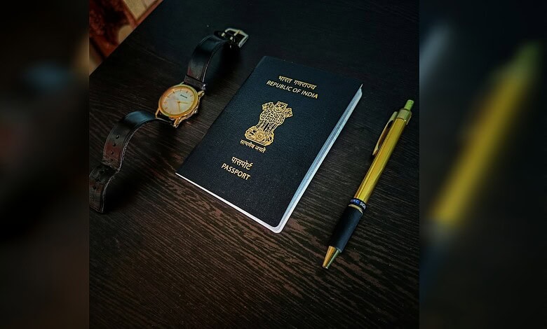 Indian passport, watch, and pen arranged on a dark wooden surface.