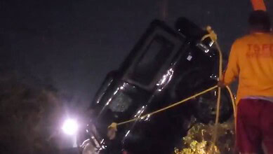Emergency responders attending a nighttime car accident scene with a vehicle on its side.