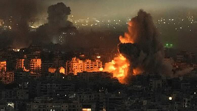 Large explosion with smoke rising over a cityscape in South Lebanon at night.