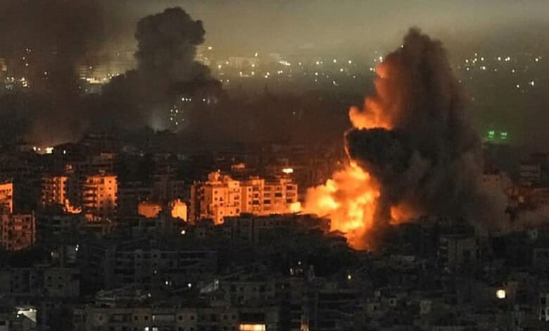 Large explosion with smoke rising over a cityscape in South Lebanon at night.