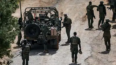 Israeli soldiers stand beside a military vehicle in southern Lebanon during a security operation.